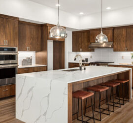 A modern kitchen with a white stone countertop and wood cabinetry.